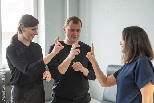 Caucasian woman teaching sign language to man and woman. 