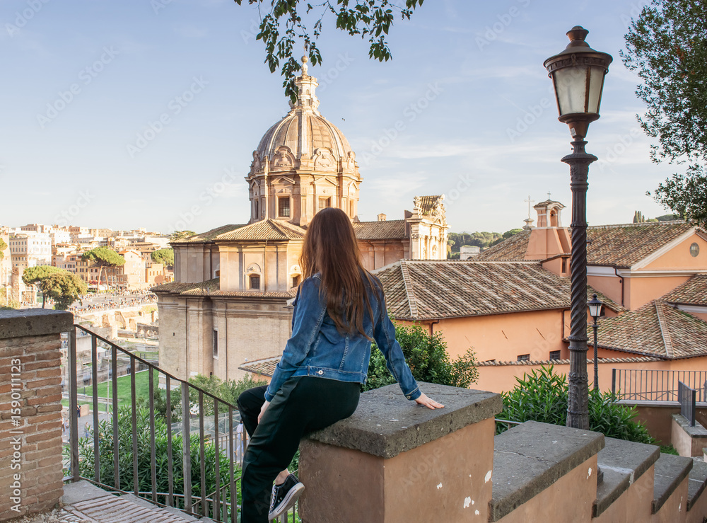 Fototapeta premium Mujer aventurera y empoderada de viaje mirando el casco histórico de una antigua ciudad europea. Paseando por Roma. Turismo y estilo de vida.
