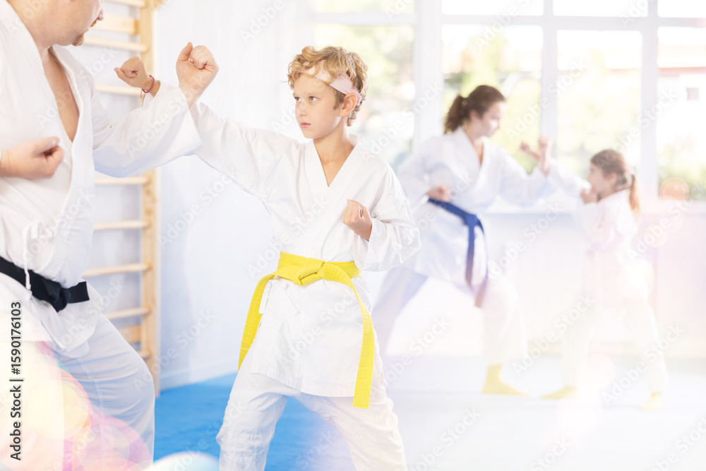 Obraz premium Interested father imparting martial arts wisdom to preteen son in sparring during training session. Sporty family legacy concept