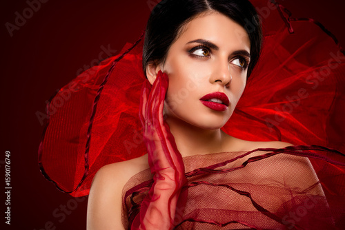 Beautiful young brunette woman in red attire posing with elegance and charm, showcasing sophisticated beauty