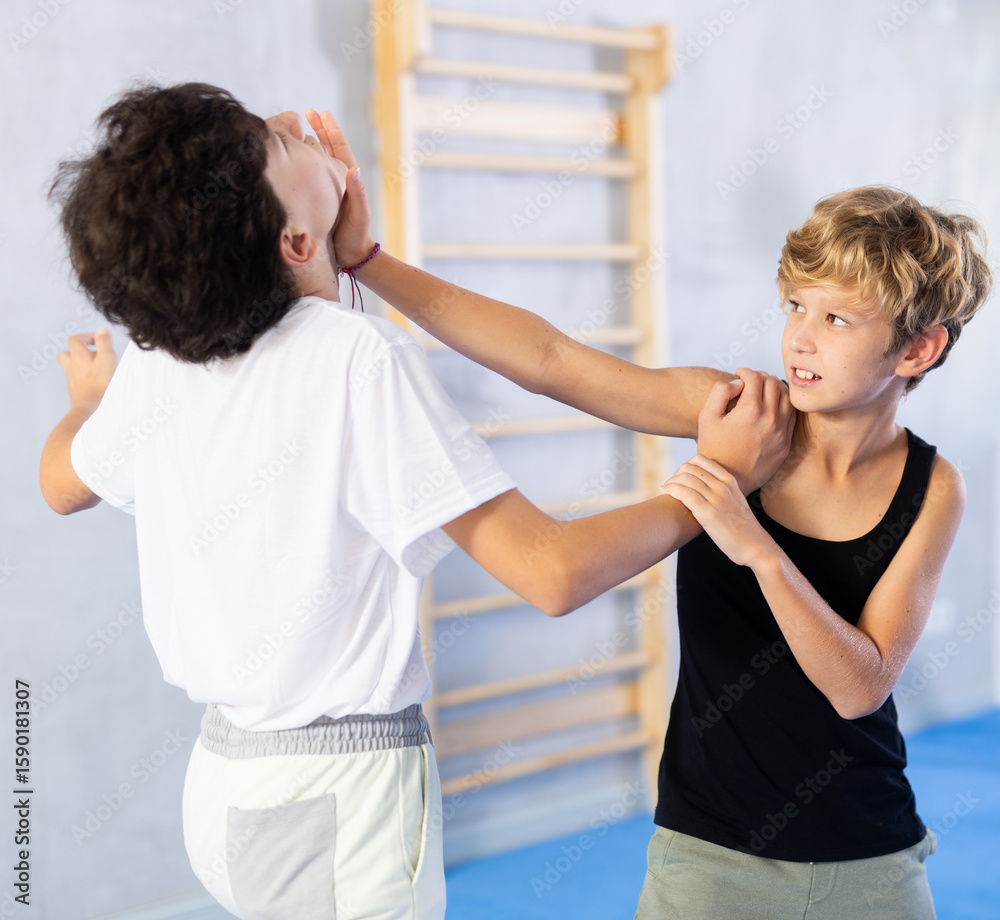 Obraz premium Children in sparring improve skill of performing strangulation and neutralizing enemy during krav maga class. Pupils strike out at mandible and body at self-defense lesson