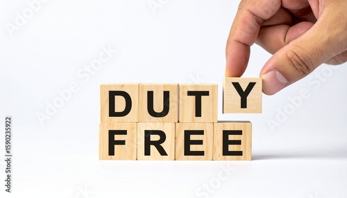 A hand carefully positioning the letter Y to complete the DUTY FREE block letters, symbolizing the removal of taxes on goods