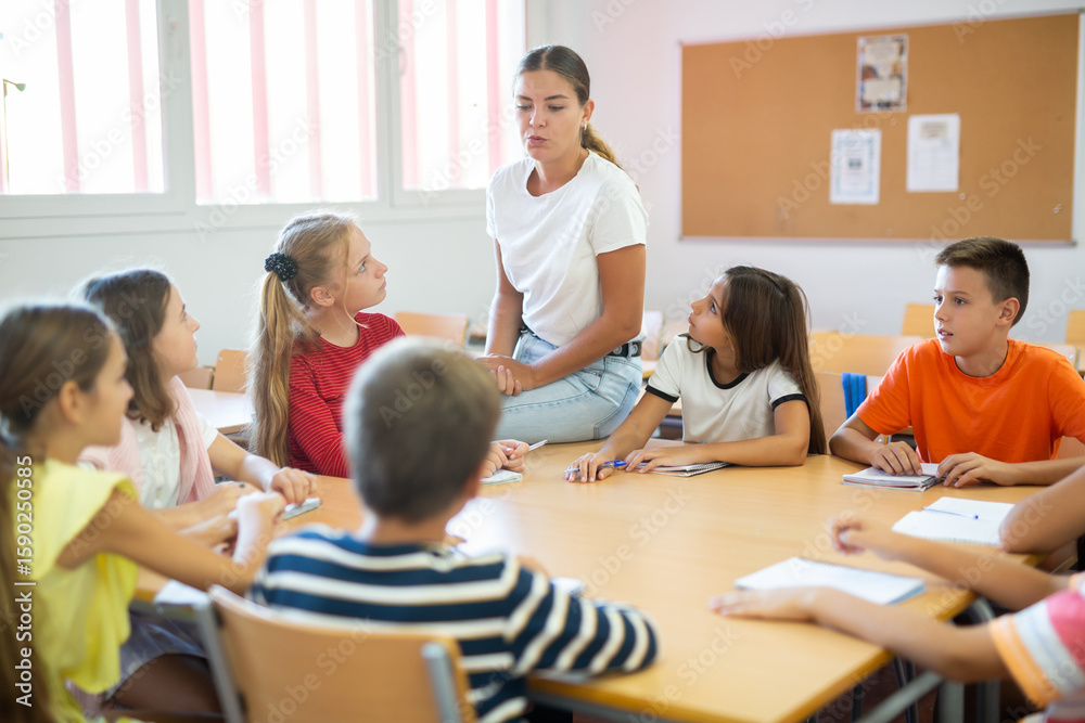 Group of girls and boys studying in school, sitting around desks and attending teacher's lecture. Group of girls and boys studying in school, sitting around desks and attending teacher's lecture.