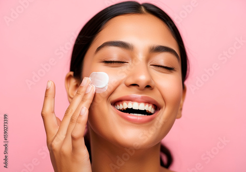 Indian Woman Smiling While Applying Moisturizer to Face
