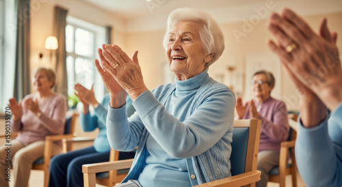 A group of elderly women clapping hands while sitting in chairs in a well lit room with a window behind them