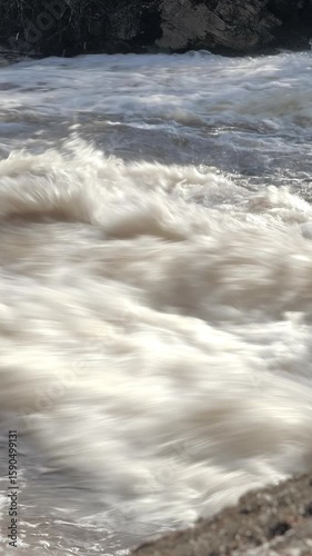Fast flowing river and the rocks surrounding it. geology shot with the camera slowly moving sideways and upwards. Vertical video.