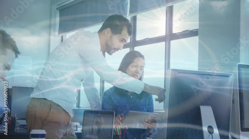 Manager guiding business project review by picking up tablet and highlighting details on monitor