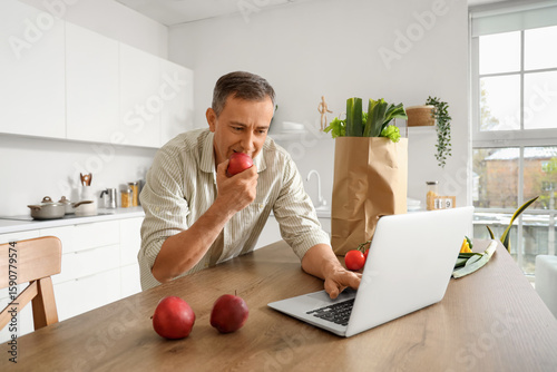 Mature man with apple using...
