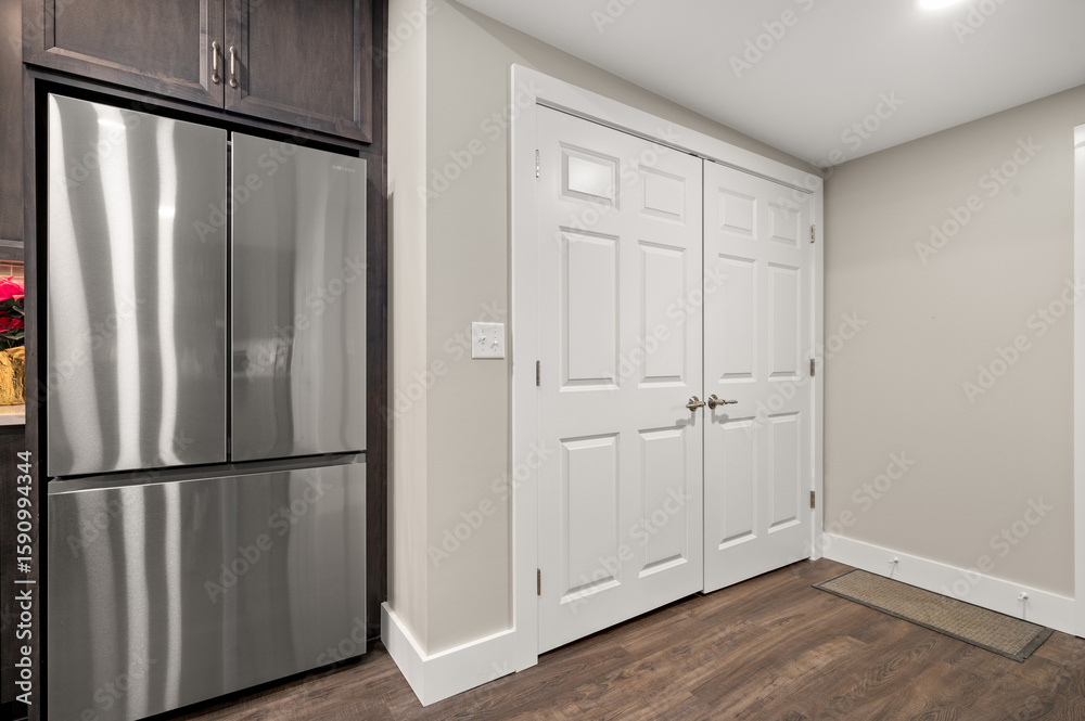 Fototapeta premium Kitchen Pantry Door Next to Stainless Steel Refrigerator