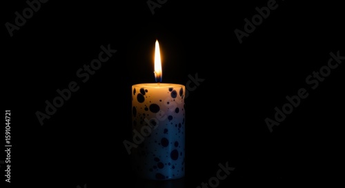 A single candle burns brightly in the dark