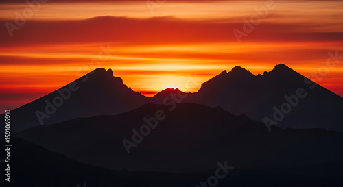 Silhouette of mountains against a vibrant orange and red sunset sky with layered clouds view - ai generated