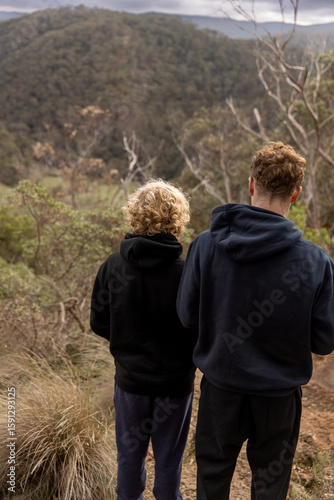 Two brothers admiring scenic view of green forest on winter road trip