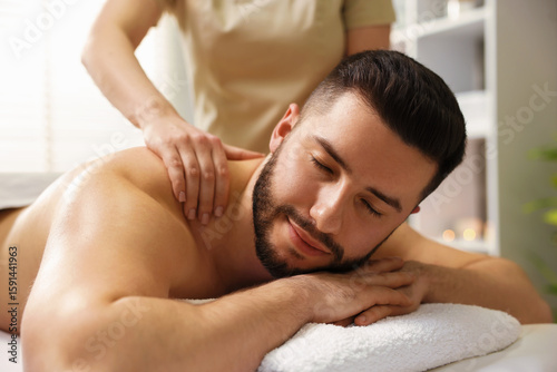 Man receiving relaxing massage in spa salon