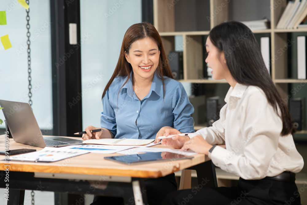 Fototapeta premium Two Asian businesswomen are having a meeting and discussing their work. 