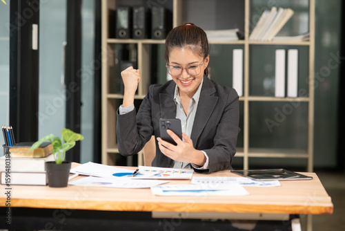 Asian businesswoman raises her hand happily, happy to be successful in her career.