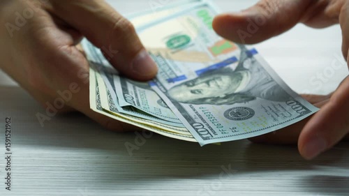Counting money at a cash register in a bank.
American dollars in the hands of a bank client and payment of taxes.
Man recounts money savings and finances.
Financial worker with American dollars