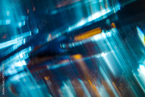 A dynamic abstract image featuring streaks of blue and teal light with motion blur and hints of orange highlights.