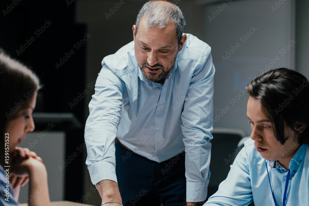 Obraz premium Senior executive mentoring junior colleague in modern office with presentation screen