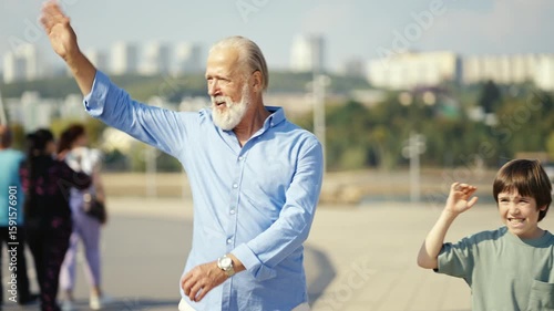 A heartwarming scene of a grandfather and grandson enjoying time outdoors, waving and sharing smiles.