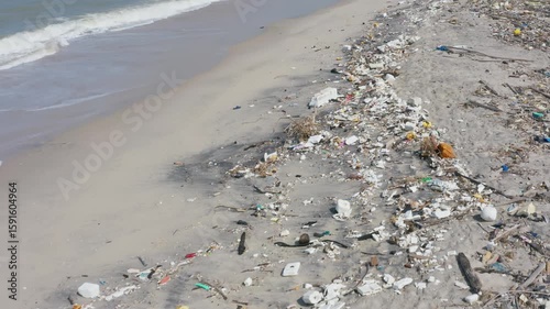 A heavily polluted beach, strewn with plastic waste and debris, highlights environmental damage and the urgent need for ocean cleanup.