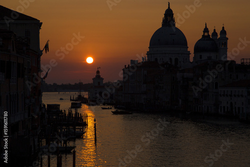 A stunning orange sunrise paints the sky above the Ponte dell Accademia, illuminating the Gran Canal and revealing the magic of Venice at dawn