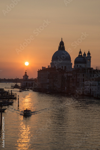 A stunning orange sunrise paints the sky above the Ponte dell Accademia, illuminating the Gran Canal and revealing the magic of Venice at dawn
