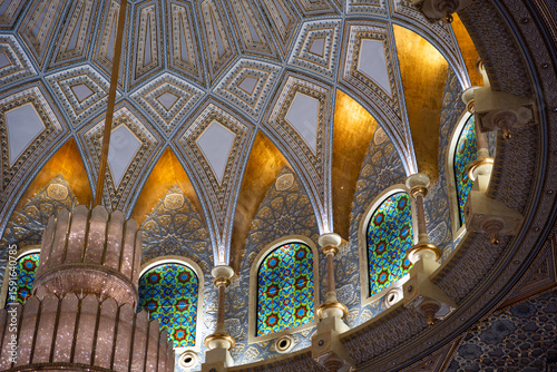 Photography An ornate ceiling with stained glass windows, intricate patterns, and a large chandelier
