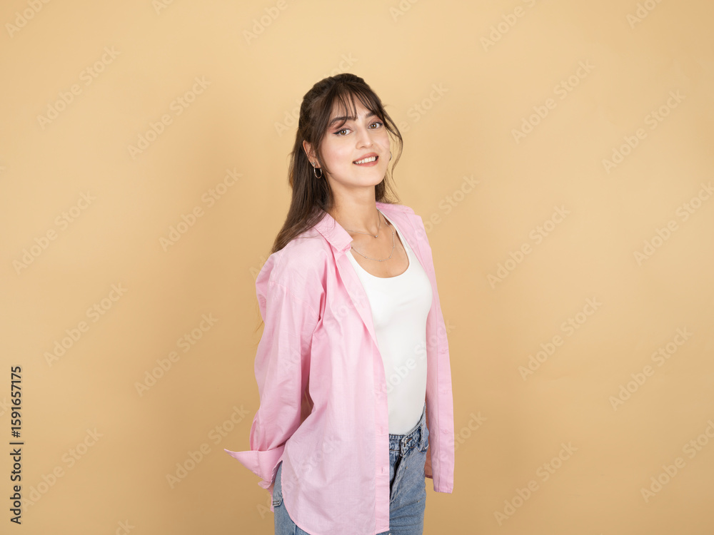 Obraz premium Carefree happy woman, side view profile portrait of young caucasian 20s brunette carefree happy woman posing isolated on beige background put her hands behind her back wear white top pink shirt.