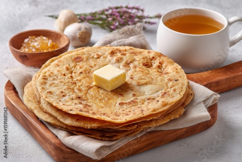 Delicious puran poli flatbread with jaggery served with tea on a rustic wooden tray