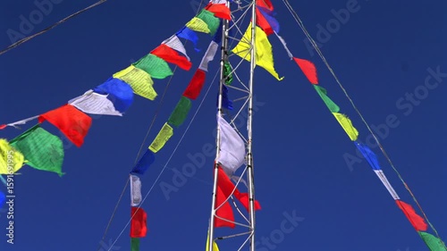 Aspen Highlands bowl blue bird sky sunny winter spring day Nepali prayer flags metal pole Colorado Snowmass Elk Mountains morning afternoon no clouds top of peak pan upwards motion