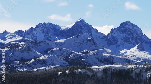 The Hemlocks Mammoth Mountain ski snowboard resort winter sunny blue sky afternoon aerial drone California The Minarets jagged towering peaks fresh deep snow clouds Inyo National Forest landscape zoom