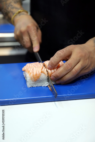 chef experto en sushi contando makis de arroz con salmón ahumado flambeado con un cuchillo y sus manos
