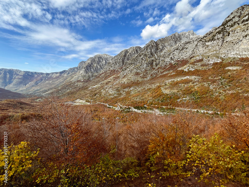 Scenic autumn view of the mountains and valley in Malësi e Madhe, northern Albania, with vibrant foliage and rugged peaks.