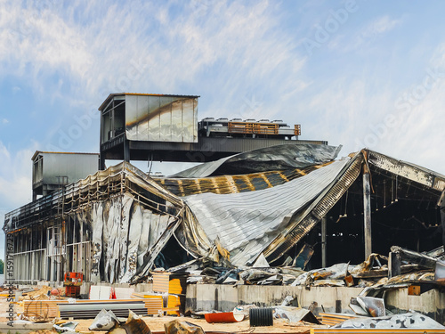Devastating aftermath of a fire, showing the ruins of a building with a collapsed roof and severe damage.