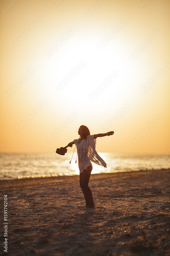 Fototapeta premium Woman Enjoying Freedom on Beach with Ukulele at Sunset