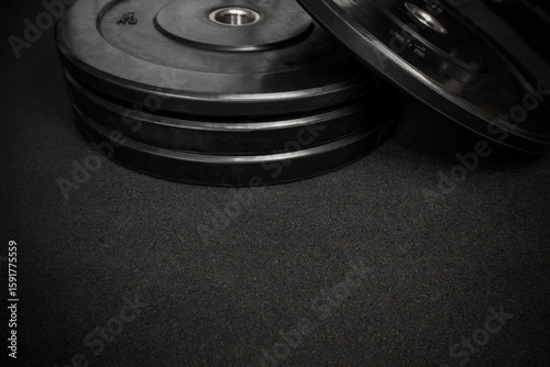 Weight plates on a black gym floor create a powerful image of strength training and fitness preparation