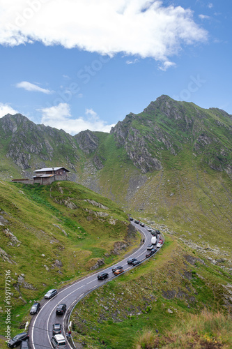 Scenic winding road in the mountains surrounded by green slopes and rocky peaks. Beautiful travel destination, Transfăgărășan, Făgăraș Mountains, Romania.