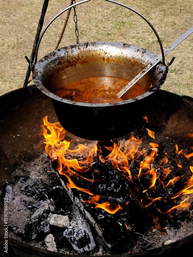 Home-cooked food over the bright red flames in a rural soup in an iron cauldron high in calorie food useful and healthy meat keto diet
