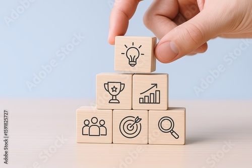 Hand stacking wooden blocks with icons representing ideas growth achievement and target.