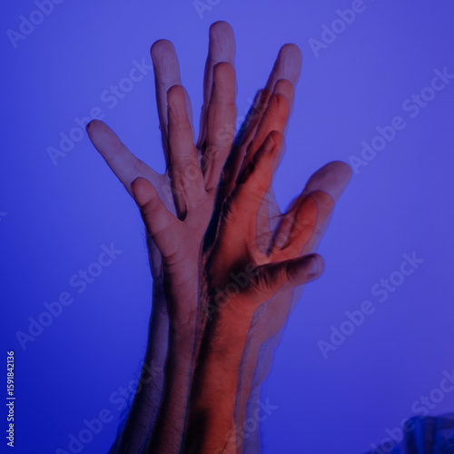 Double exposure of raised hands in motion with surreal blue and red lighting