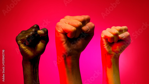 Raised fists of diverse hands symbolizing unity, strength, and social justice on red background