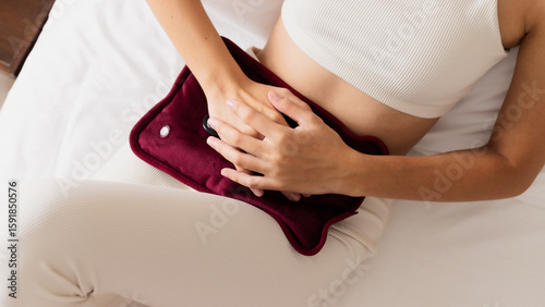 Tableau sur toile Woman lying in bed with heating pad on stomach for menstrual pain relief