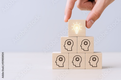 Hand stacking wooden blocks with brain and gear icons symbolizing ideas innovation and thinking process.