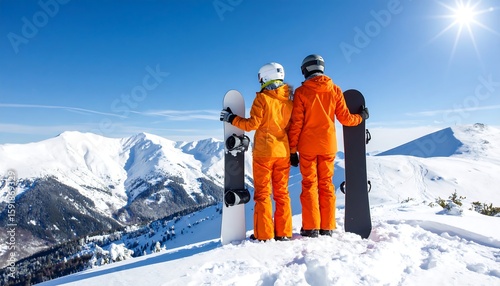 Wallpaper Mural Couple in orange ski suits stand on snowy mountaintop, holding snowboards, facing away from viewer.  Vast snowy peaks, bright blue sky Torontodigital.ca