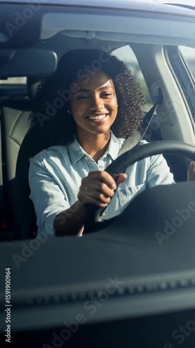 Beautiful young african american woman with curly hair driving a car and smiling, enjoying her journey on a sunny day, representing independence, car ownership and a happy lifestyle