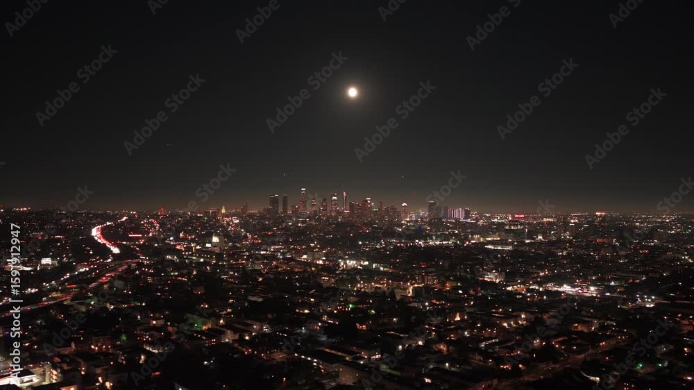 Wide dolly aerial shot of the downtown skyline at night during the buck moon in Los Angeles, California. 4K Wide dolly aerial shot of the downtown skyline at night during the buck moon in Los Angeles, California. 4K