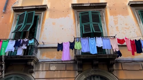 Colorful Laundry Drying on Balconies of Old European Building with Green Shutters