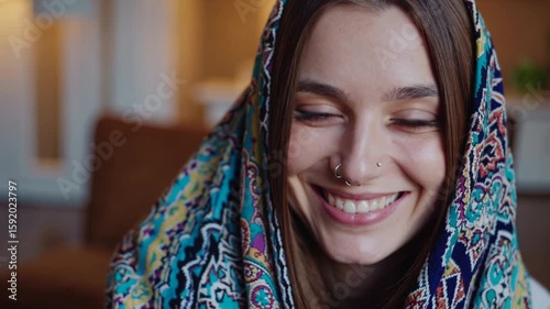 Young woman with a colorful scarf smiles warmly in a cozy living room setting during winter