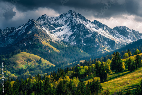 Majestic snow-capped mountain range overlooking lush green forests and rolling hills