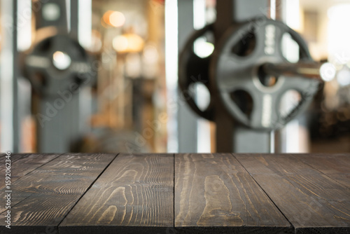 Empty wooden table top and blurred gym or fitness center as background.
